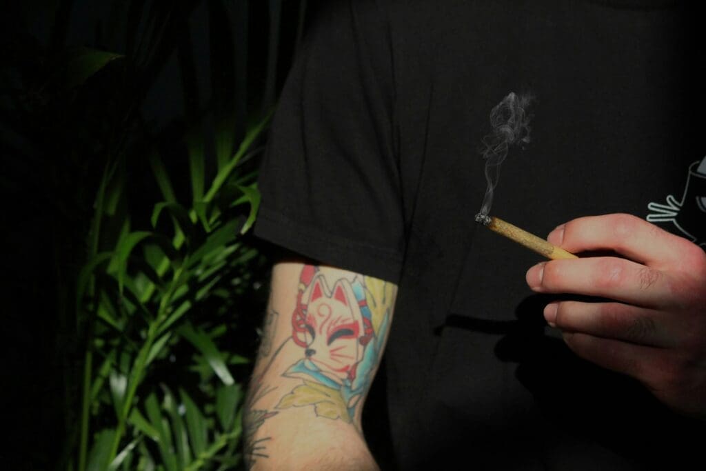 Mann hält brennenden Cannabis Joint in seiner Hand