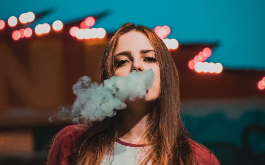 Junge Frau mit einer Cannabis-Rauchwolke vor ihrem Gesicht