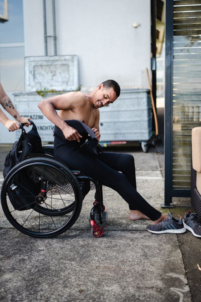 Extremsportler David Mzee beim Anziehen vor dem Sport im Rollstuhl